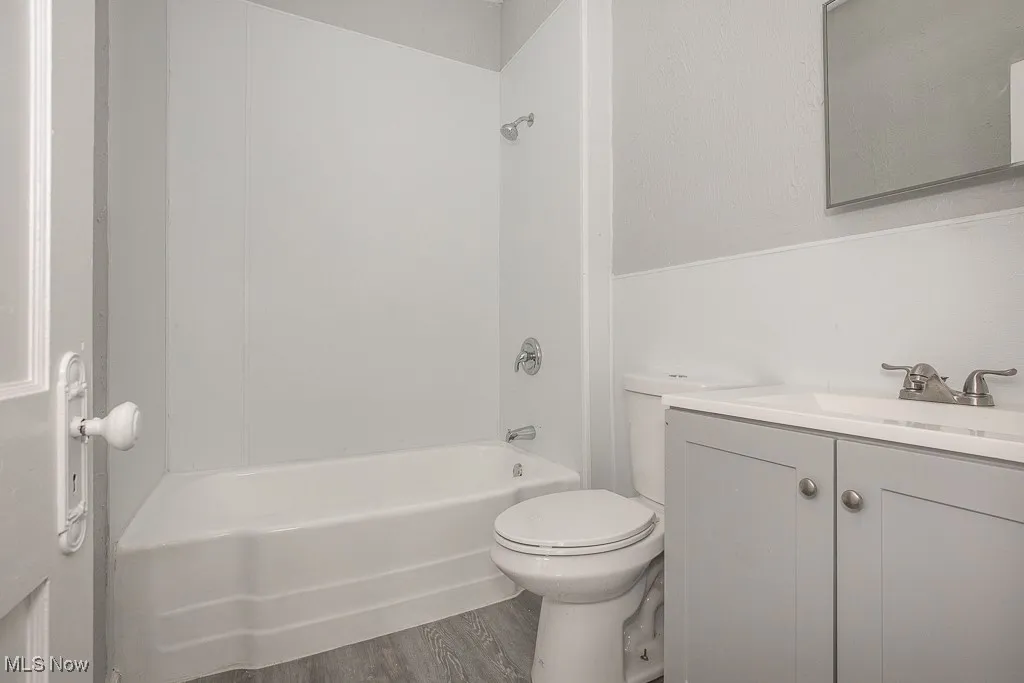 Bathroom featuring vanity, washtub / shower combination, and wood finished floors