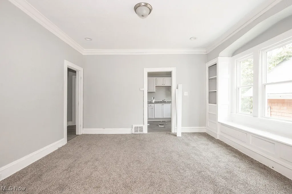 Unfurnished room with ornamental molding and light colored carpet