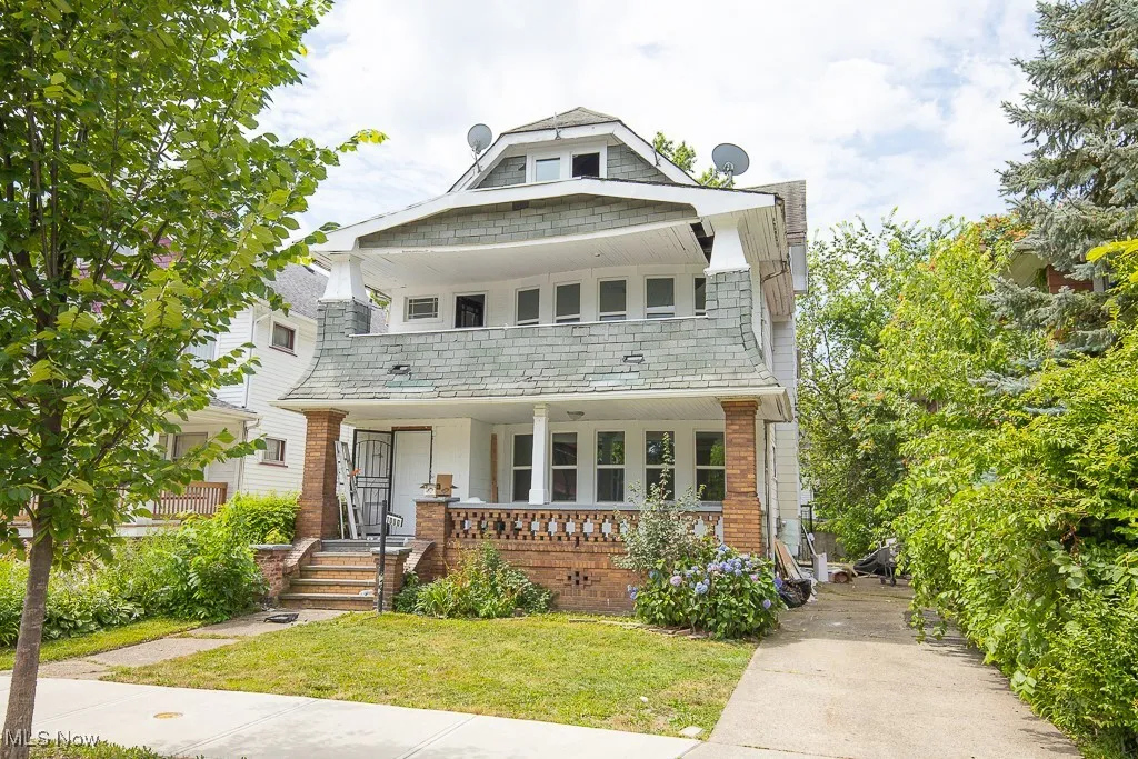 Traditional style home featuring a high end roof, covered porch, a front yard, and brick siding