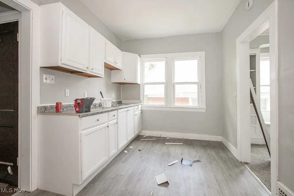 Kitchen with light wood-type flooring and white cabinets