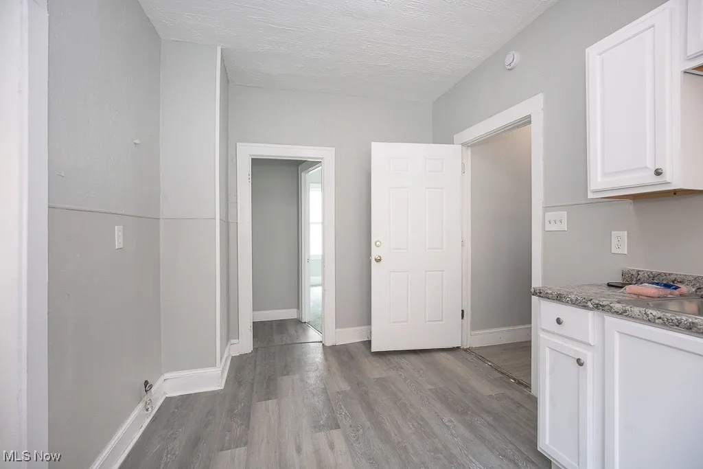 Kitchen featuring light wood-type flooring, white cabinets, a textured ceiling, and light countertops