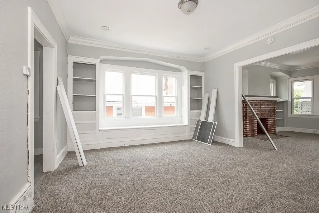 Carpeted spare room with ornamental molding and baseboards