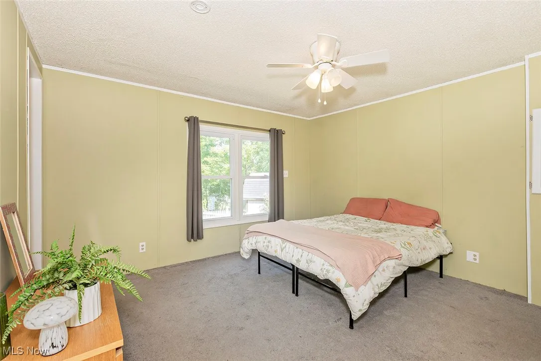 Bedroom featuring carpet floors, a textured ceiling, a ceiling fan, and ornamental molding