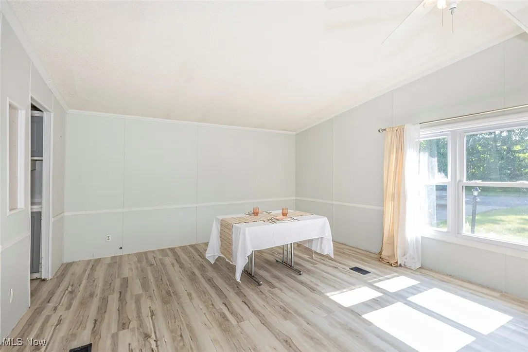 Spare room with wood finished floors, lofted ceiling, and ceiling fan
