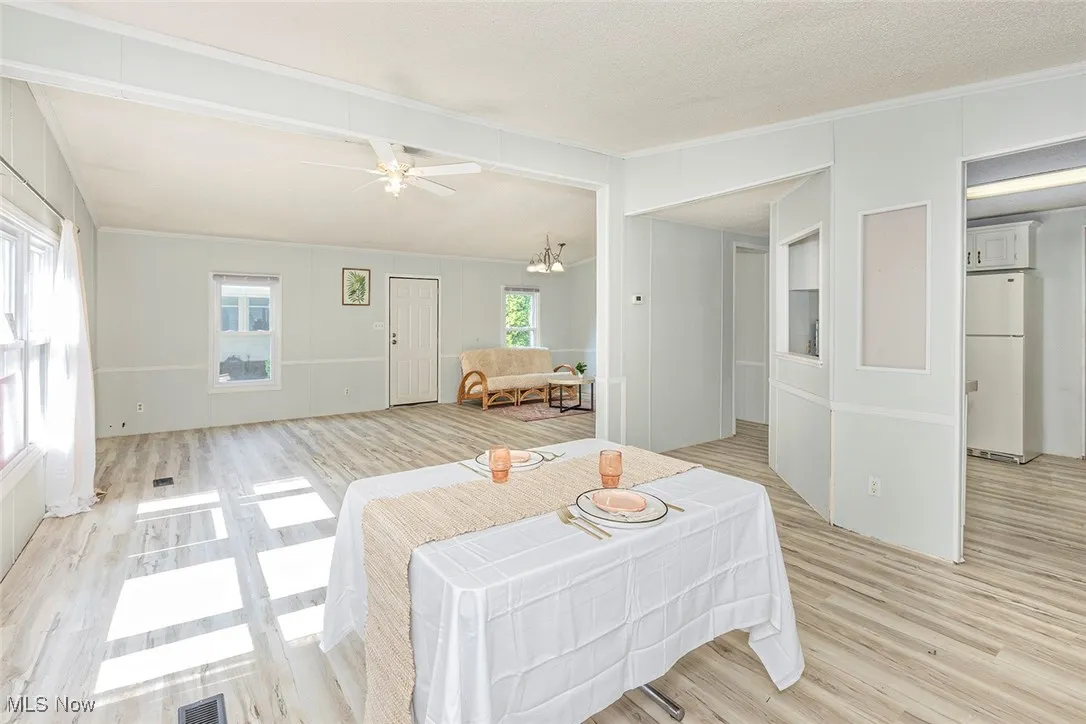 Living area featuring light wood-style flooring, crown molding, and ceiling fan