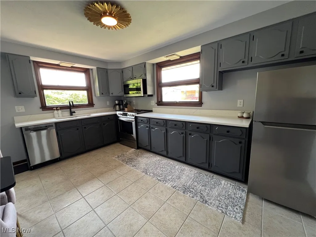 Kitchen featuring stainless steel appliances, gray cabinets, light countertops, and light tile patterned floors