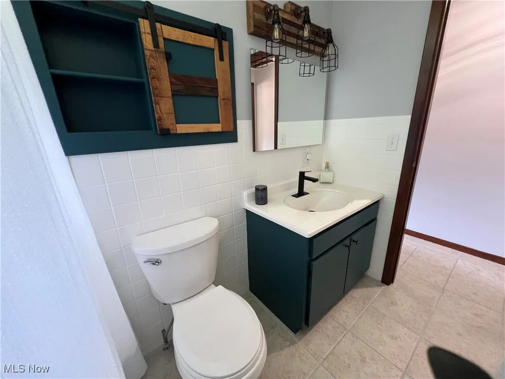 Bathroom with vanity, tile walls, and wainscoting