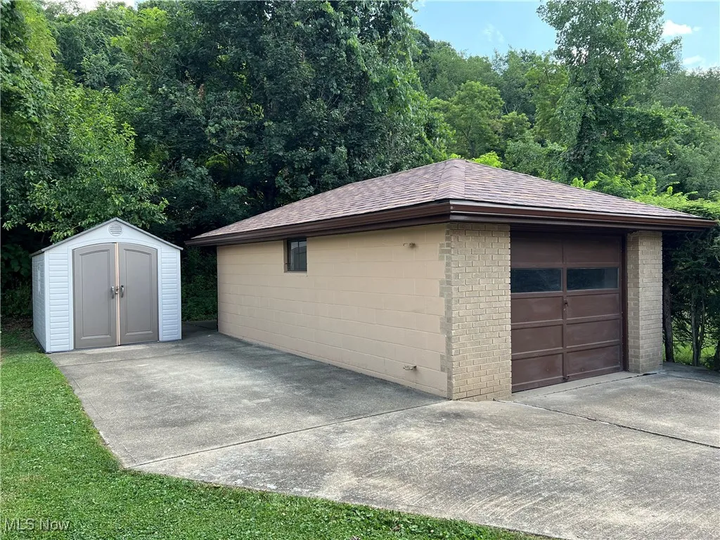 Detached garage featuring driveway and a storage unit