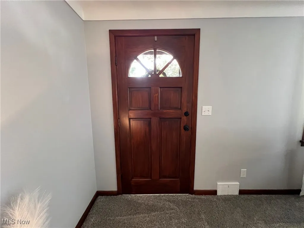 Carpeted foyer entrance with baseboards
