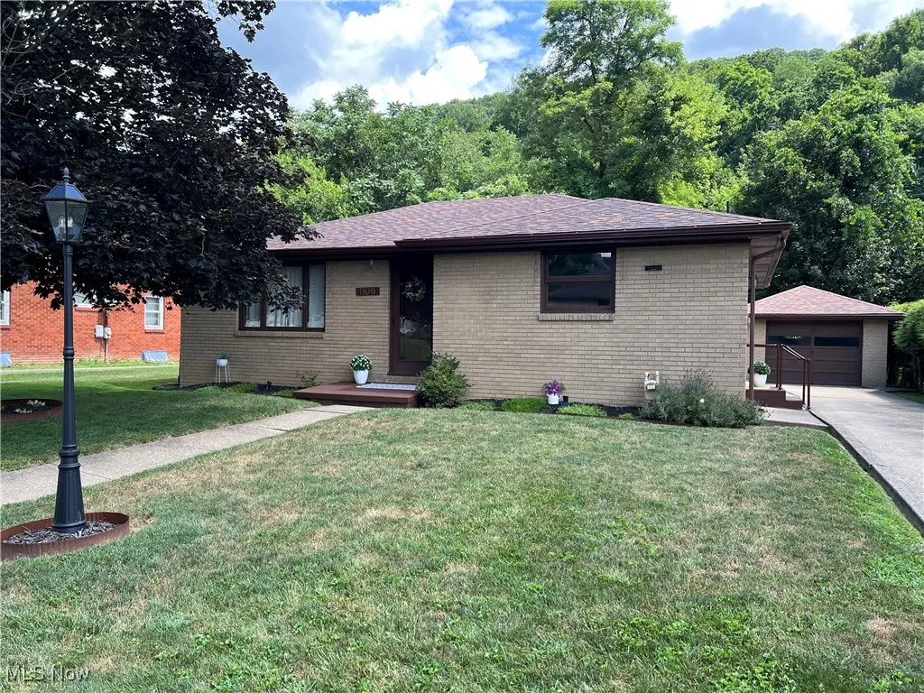 Ranch-style home with brick siding, a front lawn, an outbuilding, and a detached garage