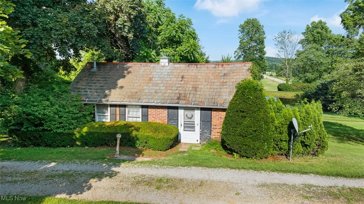 View of front of home with brick siding, a chimney, and a front lawn
