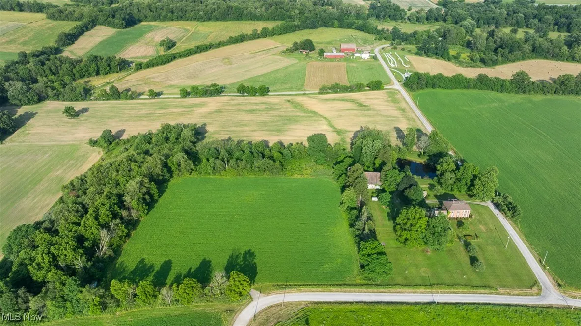 Aerial view of property and surrounding area featuring rural landscape and farmland