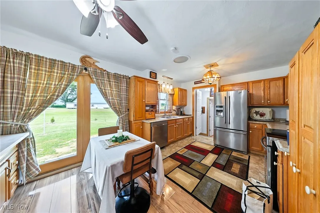 Kitchen with stainless steel appliances, brown cabinetry, a chandelier, and a ceiling fan
