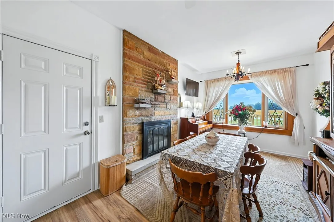 Dining room with a chandelier, a stone fireplace, and wood finished floors