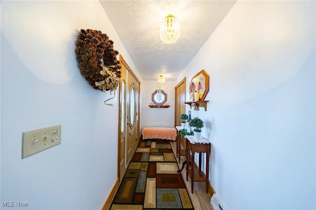 Hallway featuring a textured ceiling, a chandelier, and wood finished floors