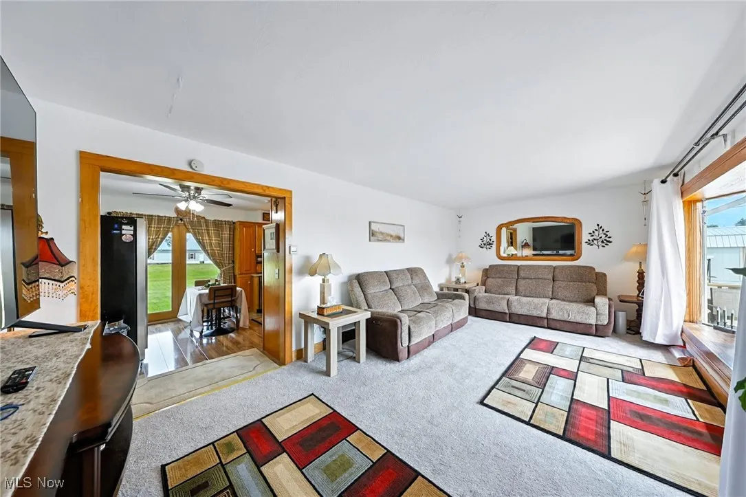 Carpeted living area featuring a ceiling fan