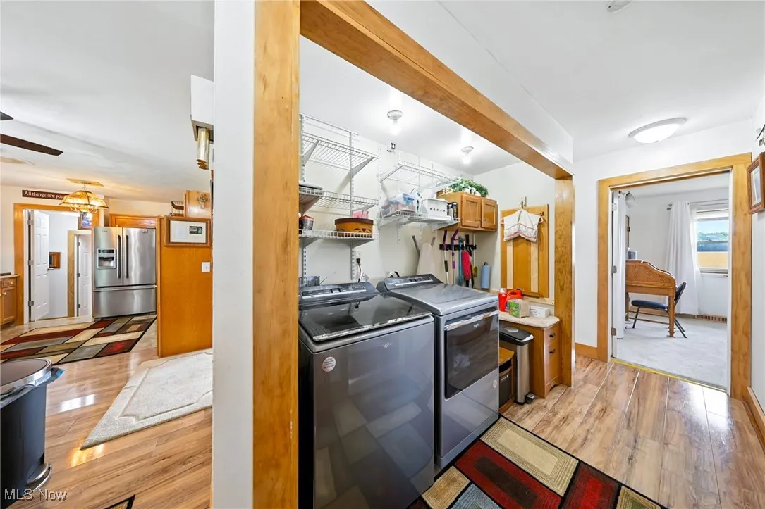 Laundry area with independent washer and dryer, light wood-style floors, and ceiling fan