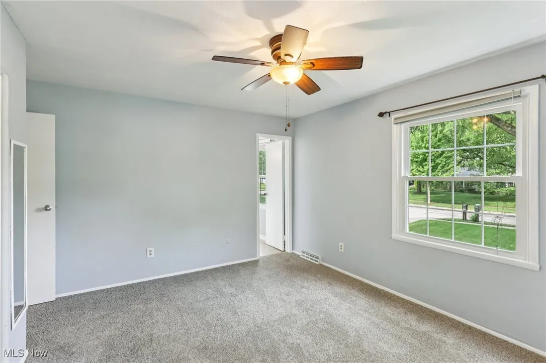 Empty room featuring a ceiling fan and carpet floors