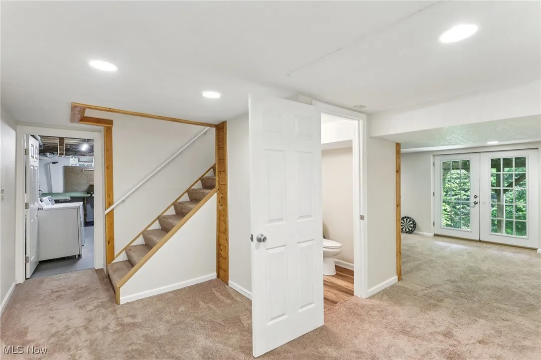 Below grade area featuring carpet flooring, washer and clothes dryer, stairs, recessed lighting, and french doors