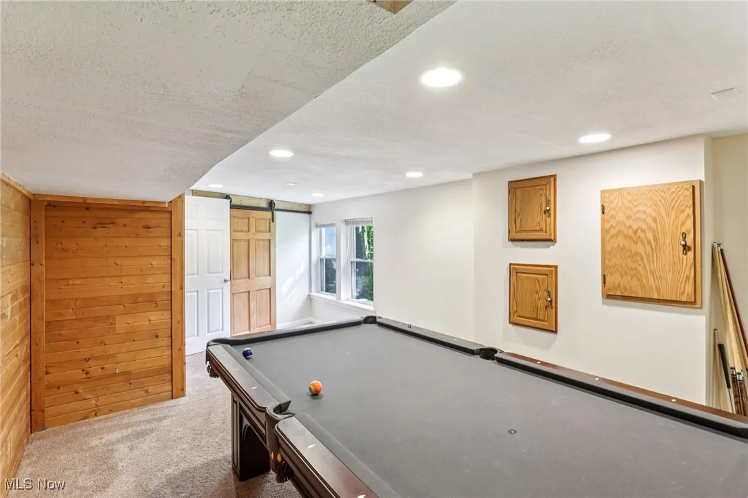 Playroom with a barn door, carpet, recessed lighting, a textured ceiling, and wood walls