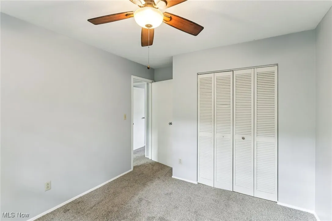 Unfurnished bedroom with carpet, a closet, and a ceiling fan