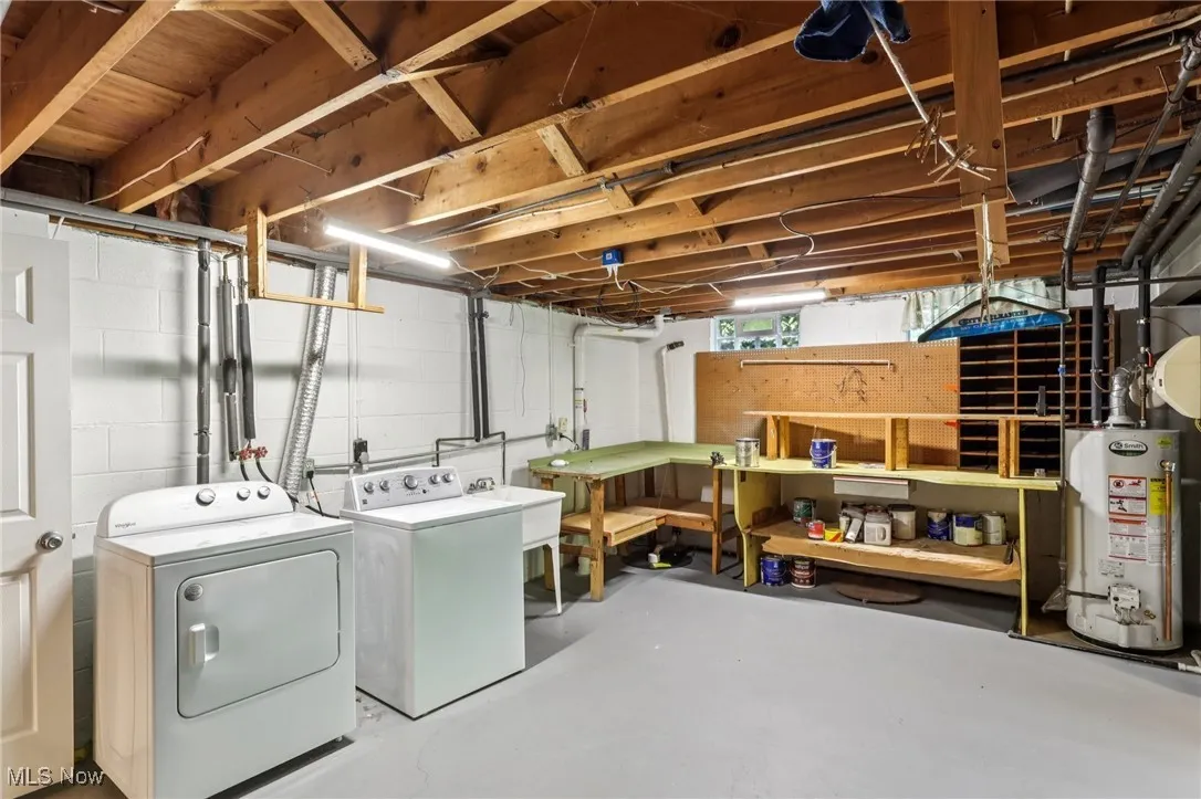 Washroom with gas water heater, washer and dryer, and a workshop area