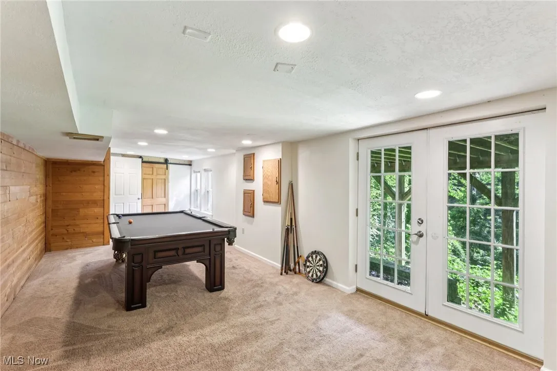 Playroom featuring a barn door, a textured ceiling, recessed lighting, light colored carpet, and wood walls