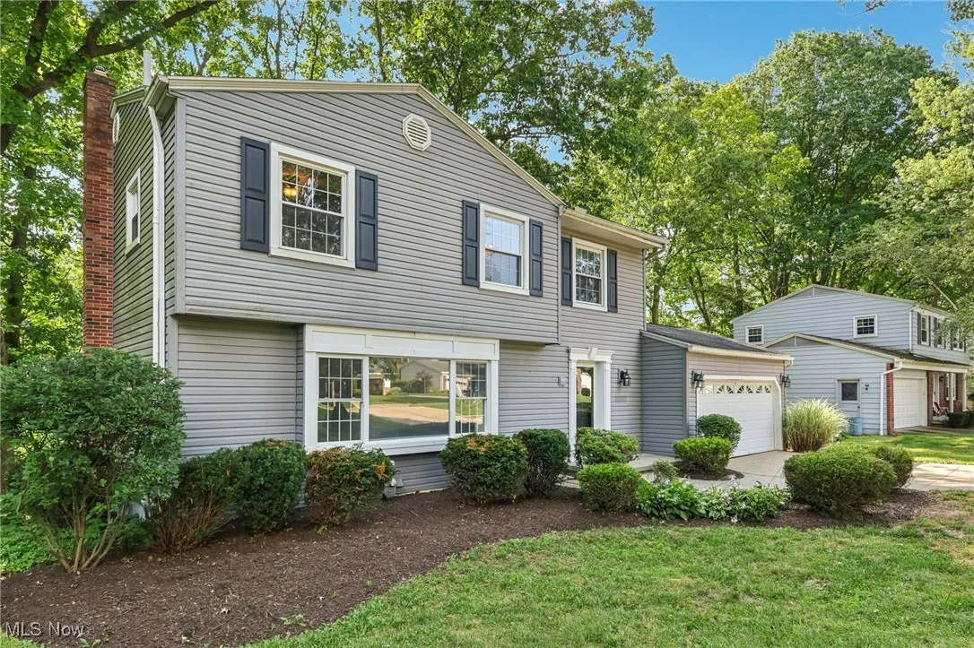 Colonial home with an attached garage, driveway, a chimney, and a front yard