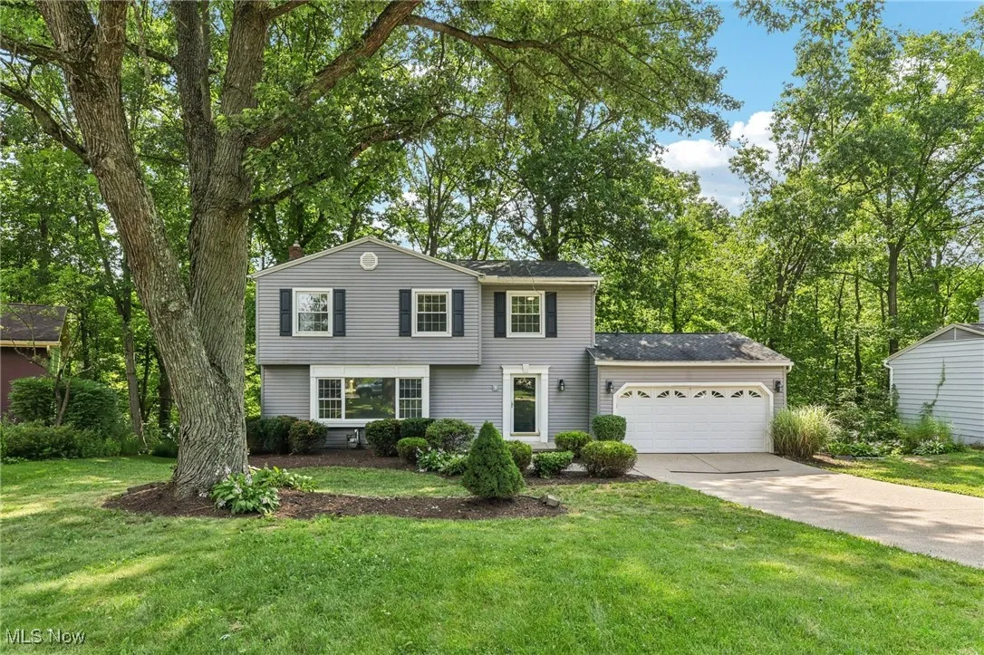 View of front of home with driveway, an attached garage, and a front yard