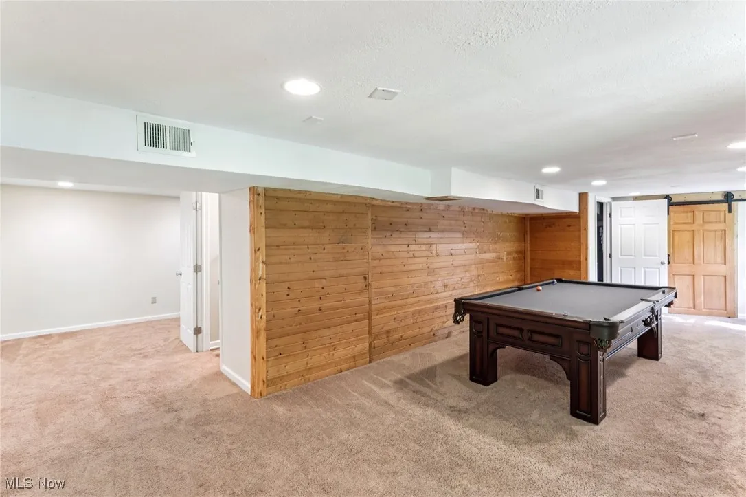 Rec room featuring carpet floors, a barn door, recessed lighting, billiards table, and wooden walls