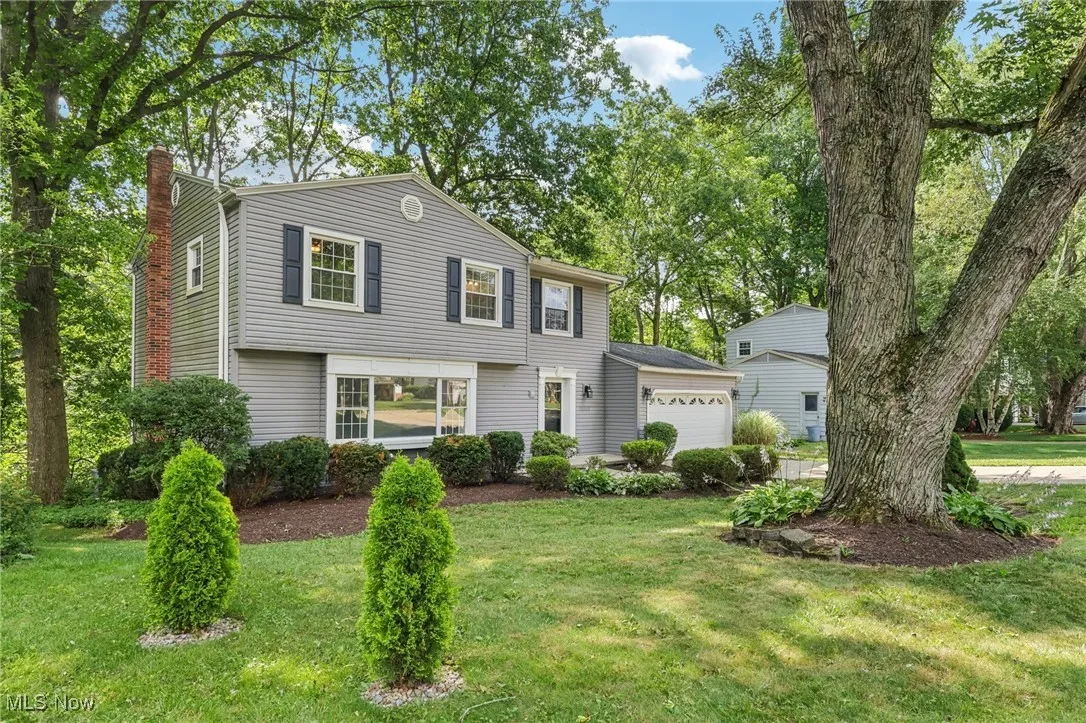 Colonial inspired home featuring a chimney, an attached garage, and a front lawn