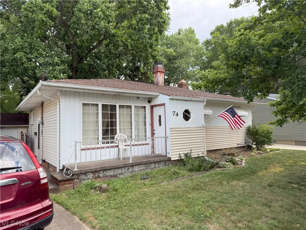View of front of house featuring a chimney, a front lawn, a porch, and roof with shingles