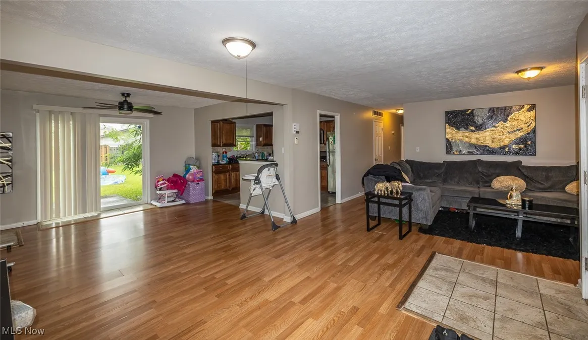 Living area with light wood-style flooring, a textured ceiling, and a ceiling fan