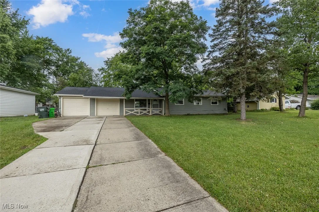 Ranch-style home featuring a garage, a front lawn, concrete driveway, and covered porch