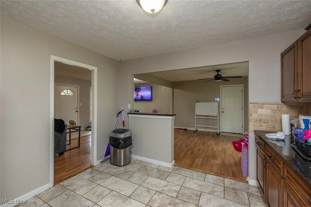 Kitchen featuring dark countertops, ceiling fan, a textured ceiling, and brown cabinetry