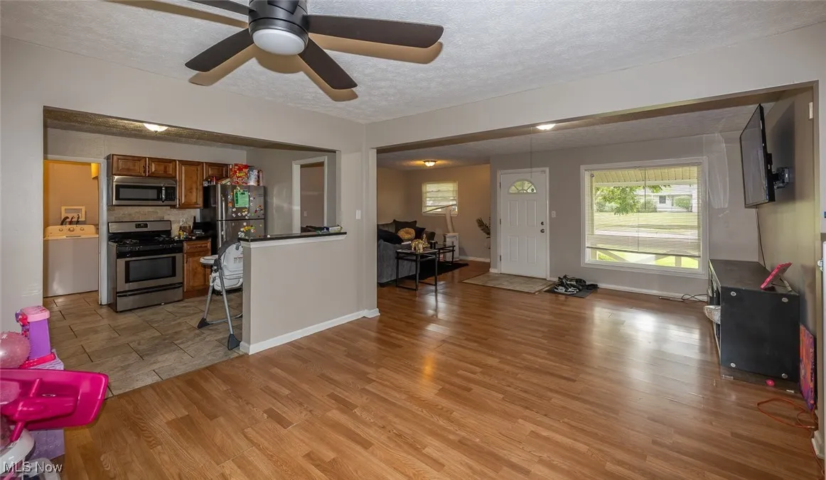 Living room with light wood-style flooring, a textured ceiling, and ceiling fan