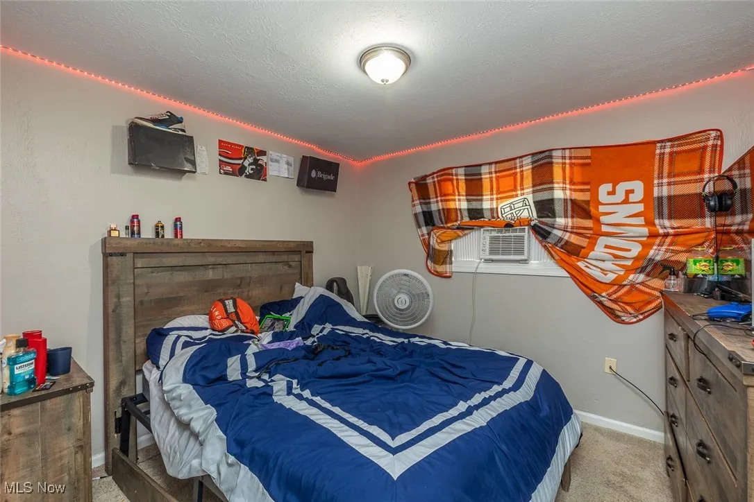Carpeted bedroom featuring baseboards and cooling unit