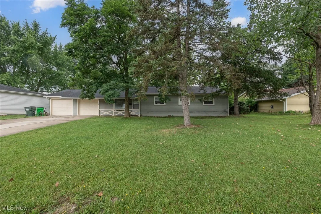 Ranch-style house featuring concrete driveway, a front yard, and an attached garage