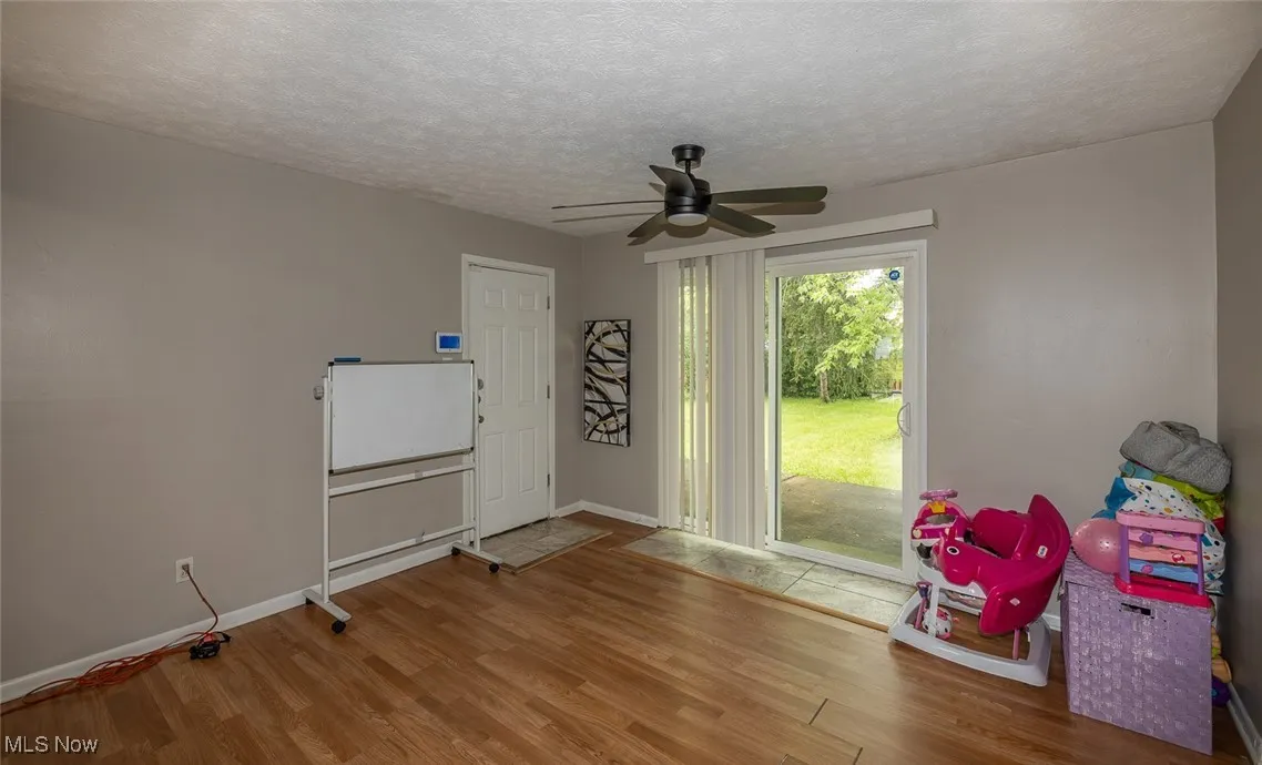 Playroom featuring wood finished floors, a ceiling fan, and a textured ceiling