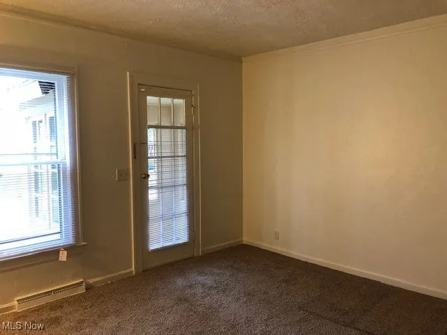 Empty room with a textured ceiling and dark carpet