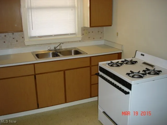 Kitchen featuring white gas stove, light countertops, and decorative backsplash