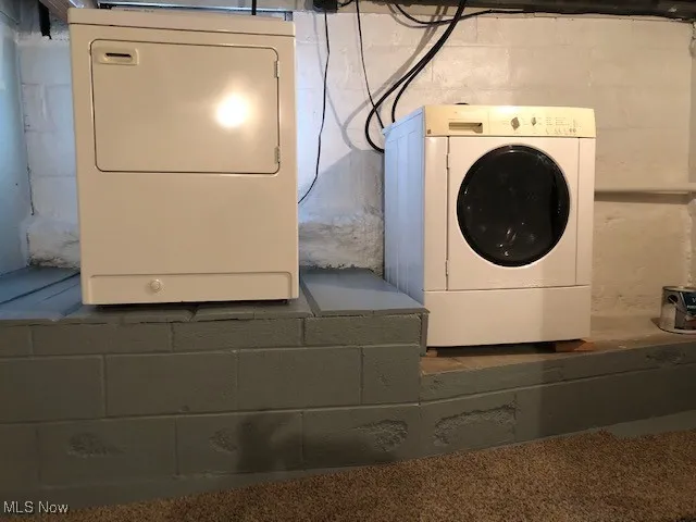 Laundry area with washer / clothes dryer and concrete block wall