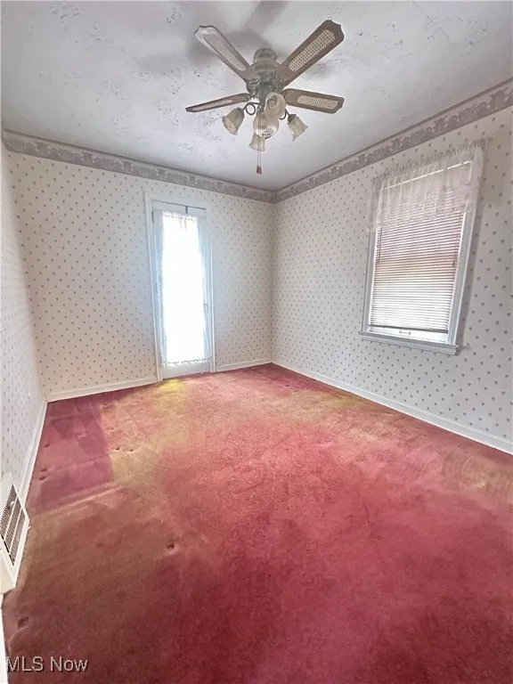 Unfurnished room featuring carpet flooring, a ceiling fan, and wallpapered walls