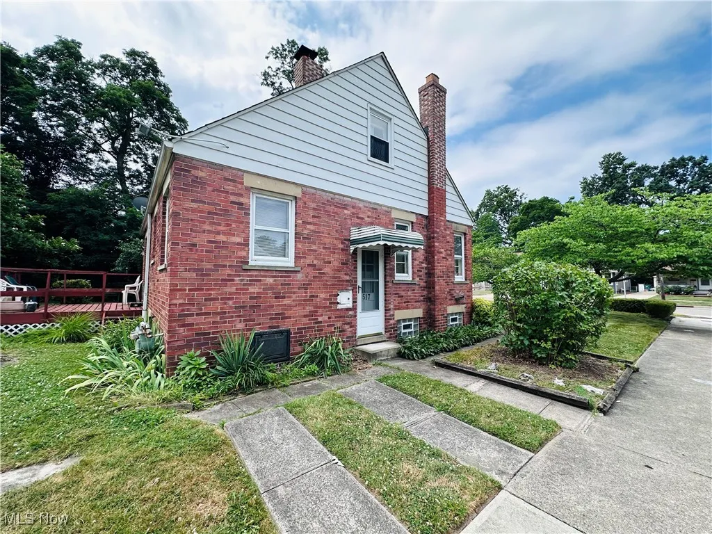 View of front facade with a chimney, brick siding, and a front lawn