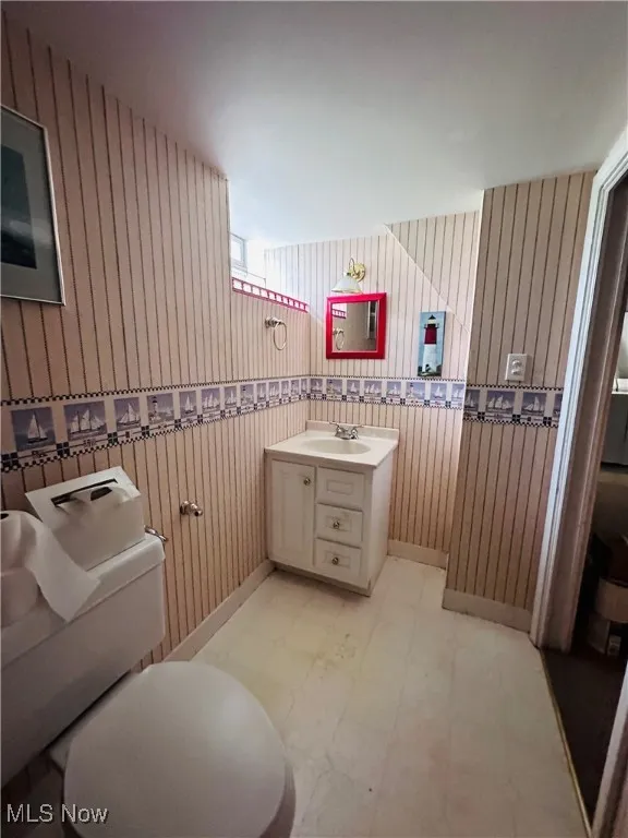 Bathroom with tile patterned floors, vanity, and wood walls