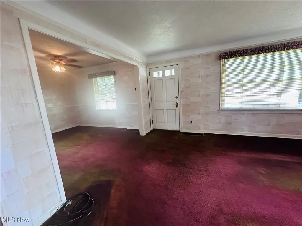 Entrance foyer featuring dark colored carpet and baseboards