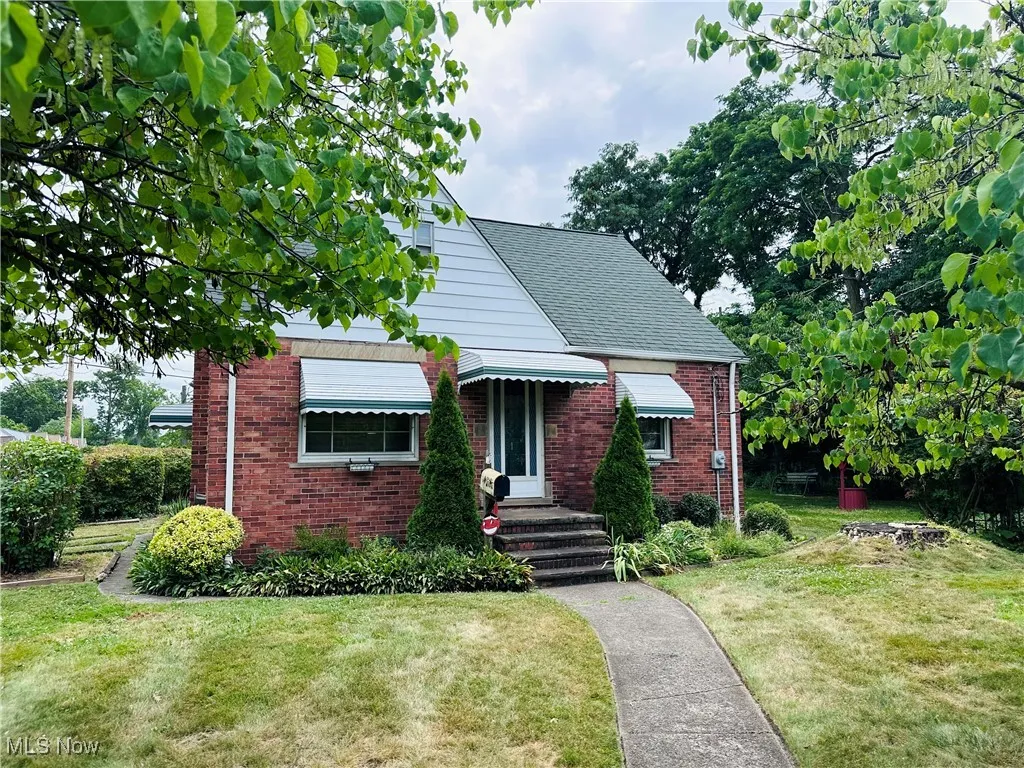 Bungalow-style home with brick siding, a front lawn, and roof with shingles