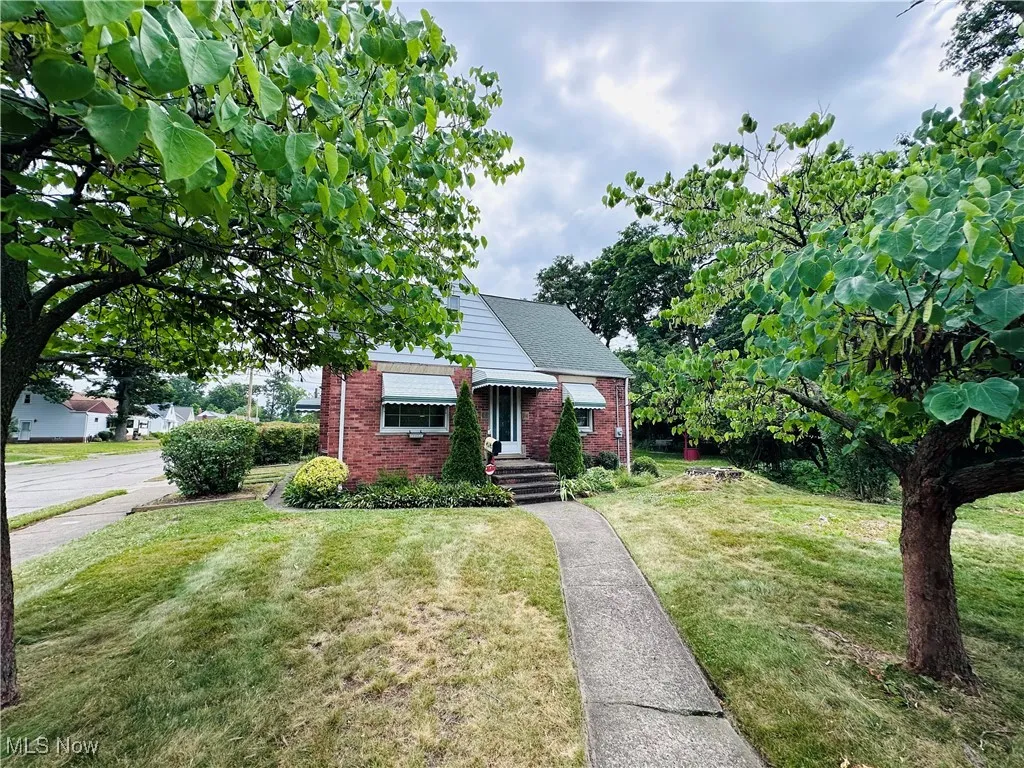 Bungalow with brick siding and a front lawn