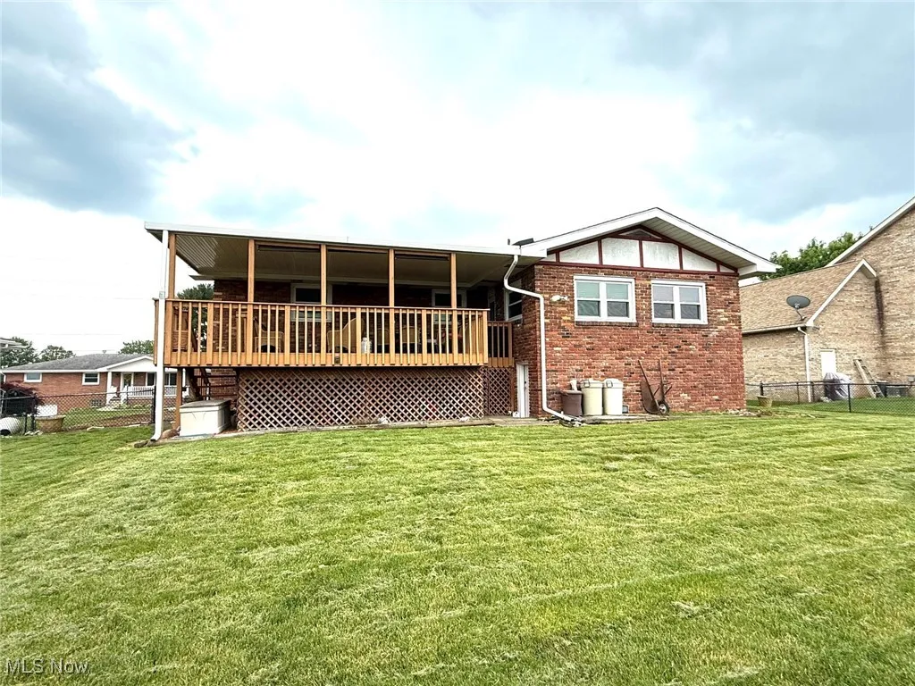 Back of home with brick siding and a wooden deck