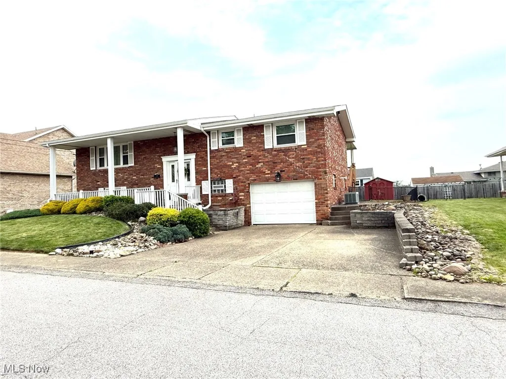 Front of home featuring brick siding, driveway, an attached garage, and a porch